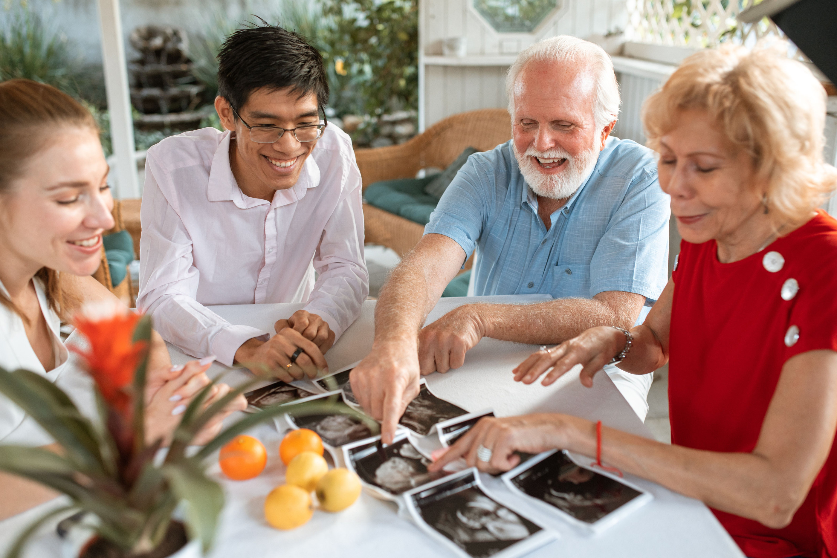 Three generations of a family sitting around a table, looking at something together.